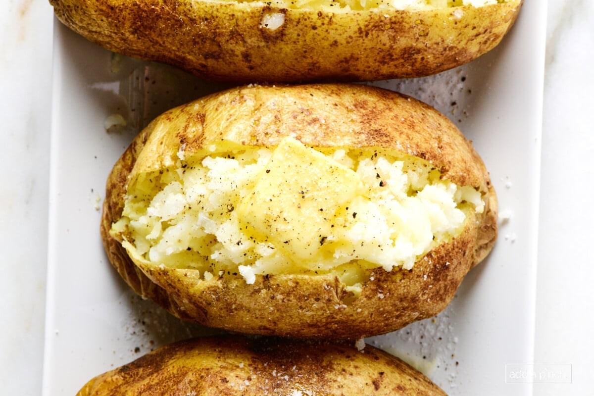 Baked potatoes on a white platter.