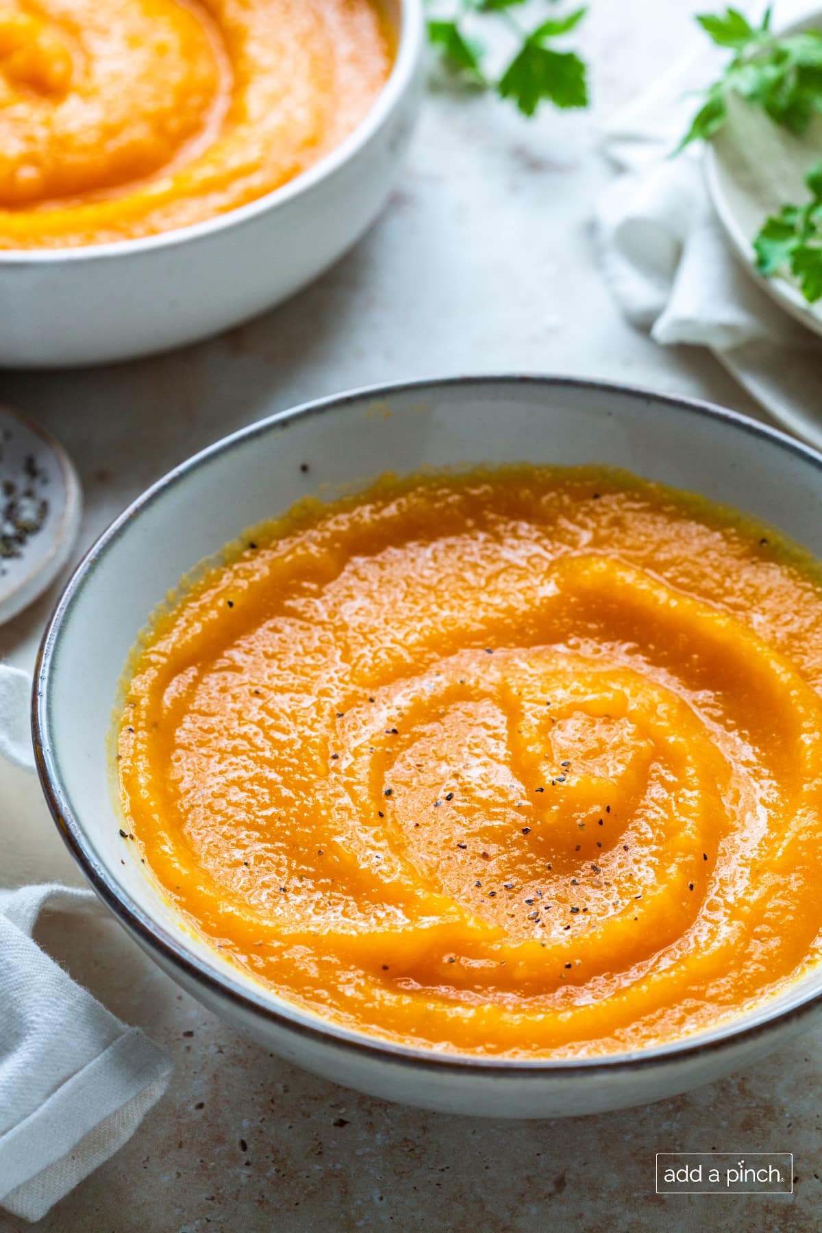 Roasted butternut squash soup in white bowl with dark edge.