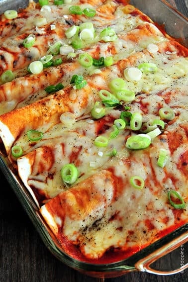 Photo of chicken enchiladas with cheese and green onions topping.