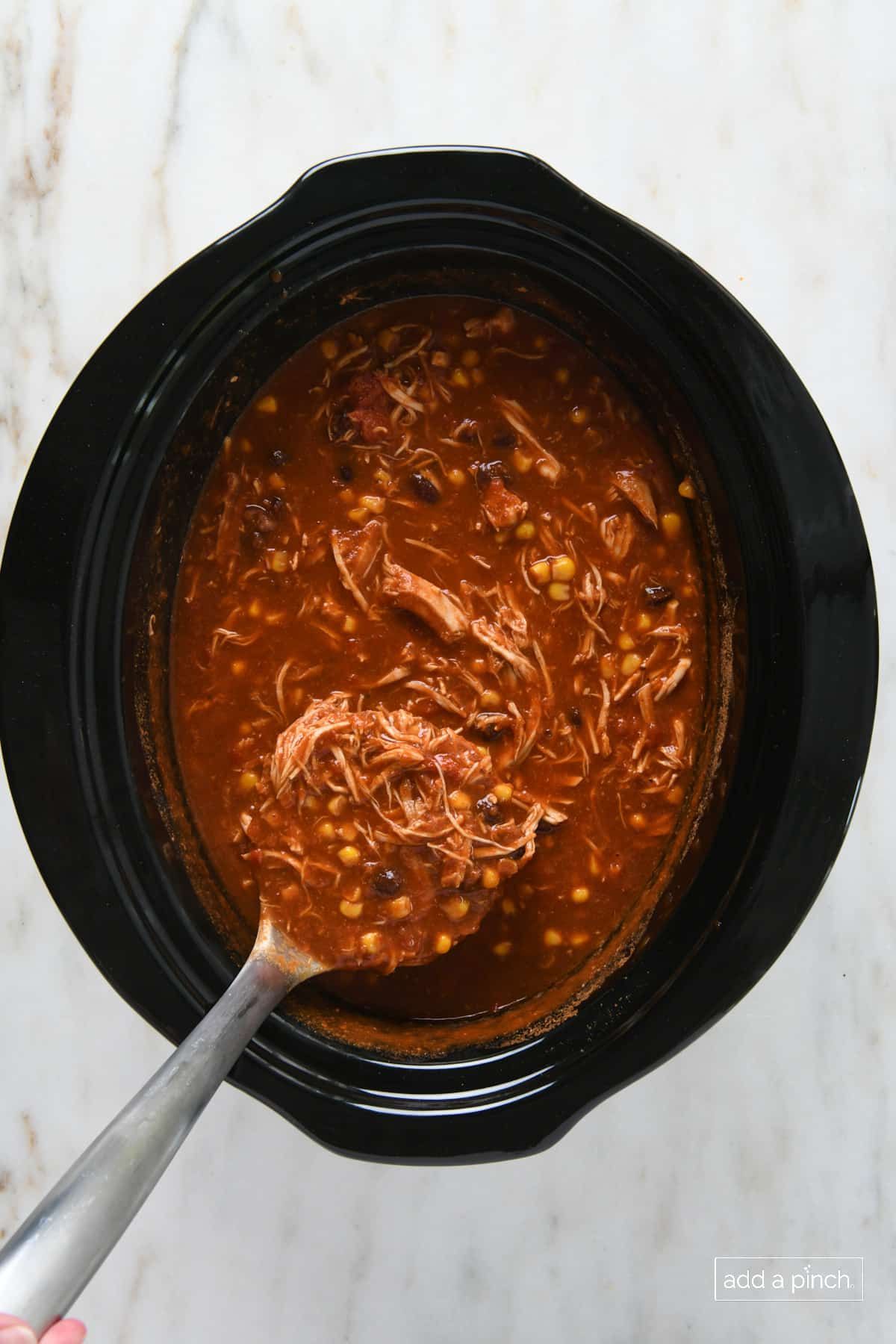 Pot of cooked chicken tortilla soup with shredded chicken.