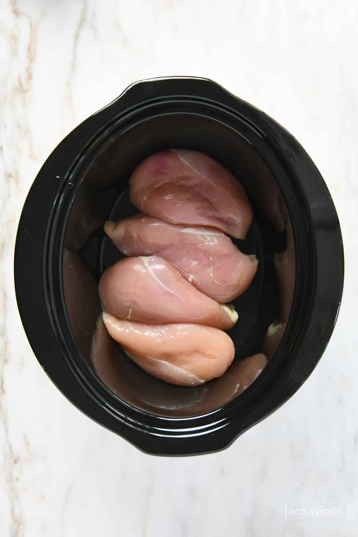 Chicken breasts in a pot to cook.