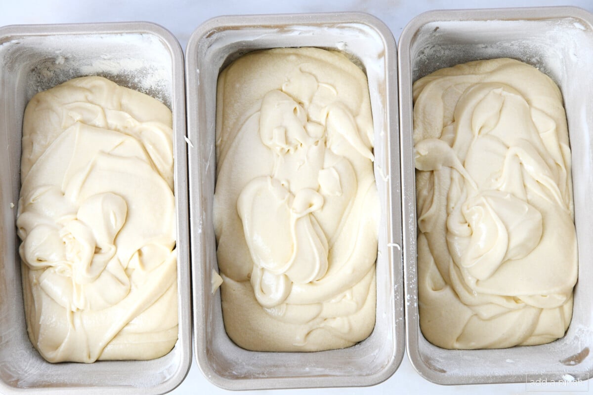 Three loaf pans have pound cake batter in them and they are ready for baking.