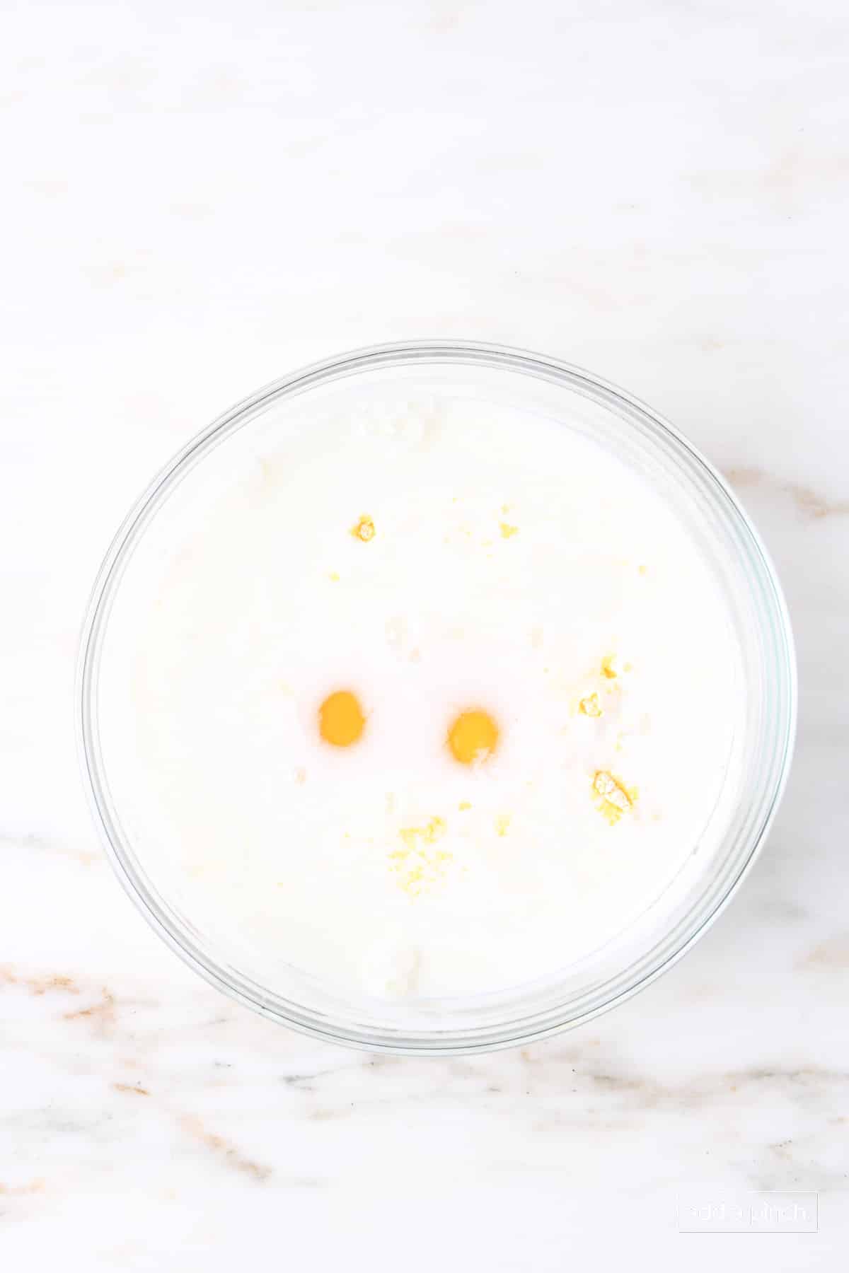 Eggs added to buttermilk and cornmeal mixture in a glass bowl.