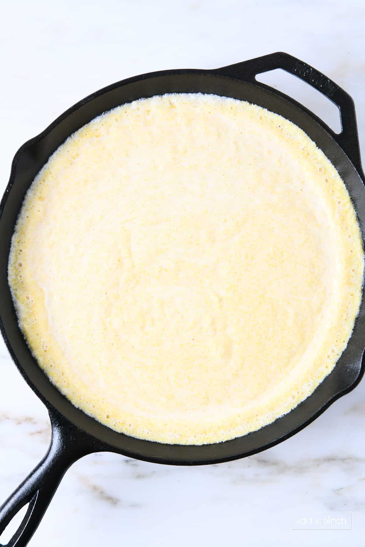 Cornbread batter in a cast iron skillet ready to be baked.
