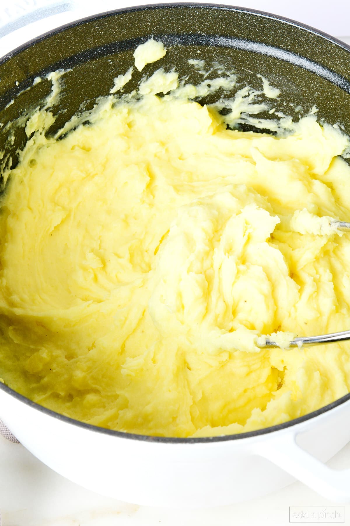 Buttery and creamy mashed potatoes in a white Dutch oven.