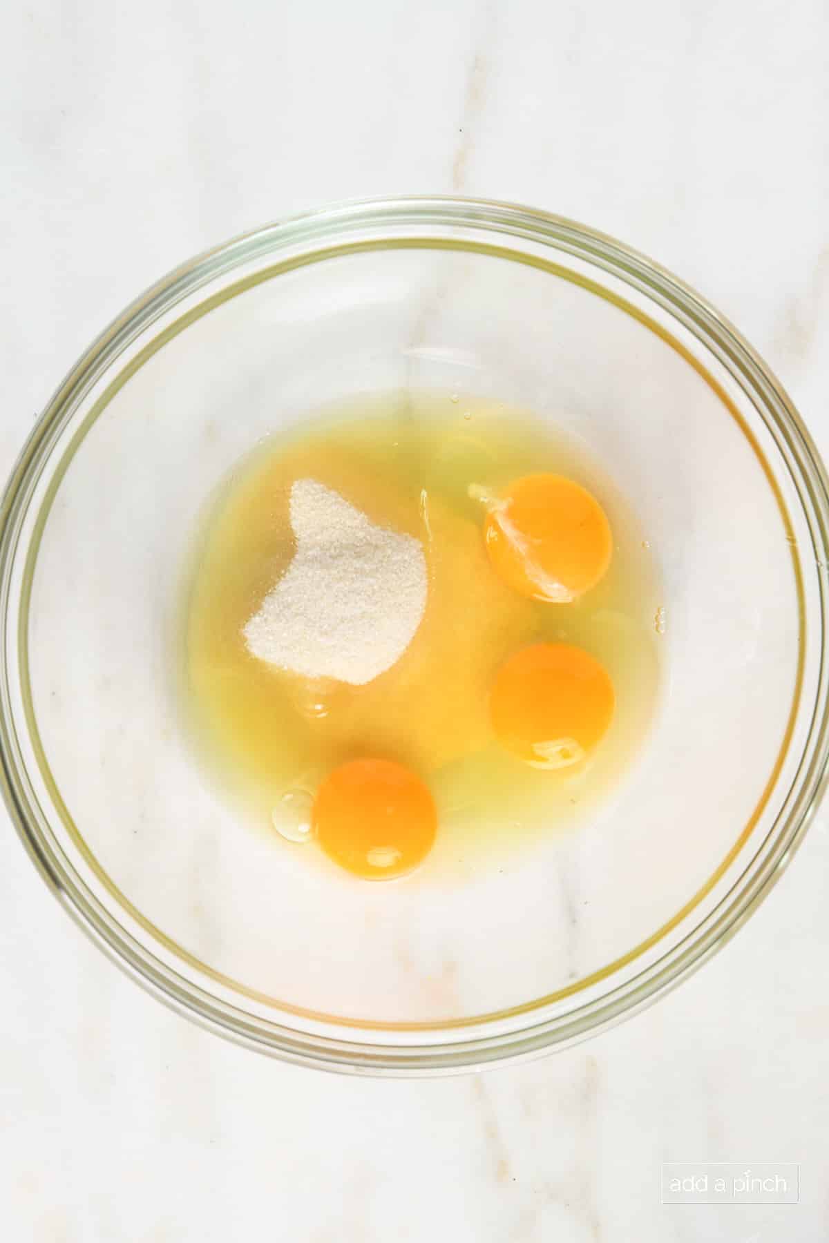 Mixing bowl with three eggs, granulated sugar and salt.