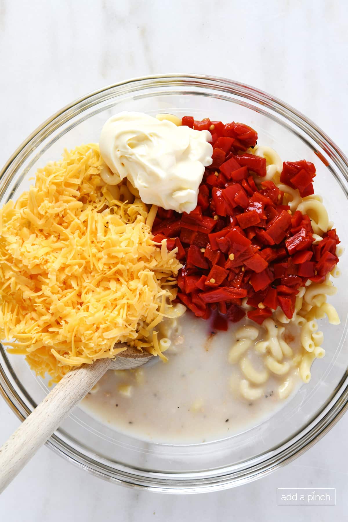 Glass bowl with noodles, cream of chicken soup, shredded cheese, mayo, and pimentos.