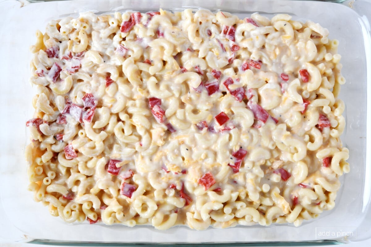 Glass baking dish holds macaroni with cheese, pimentos throughout ready to top and bake. 