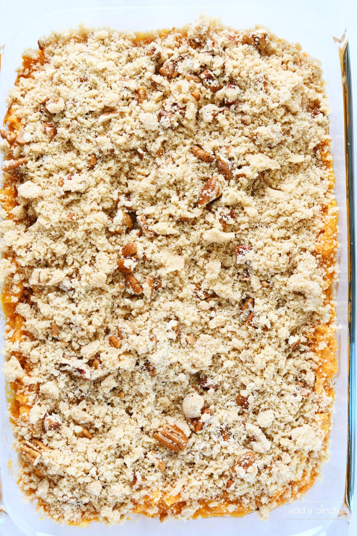 Crumble topping spread on top of an unbaked casserole in a baking dish.