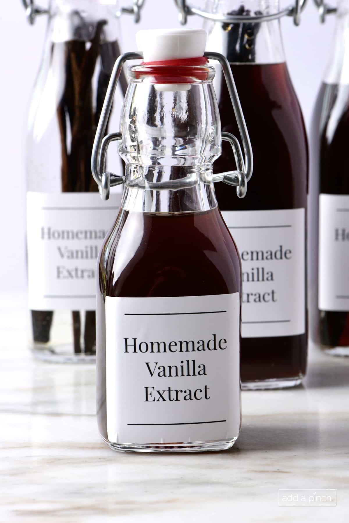 Bottles of homemade vanilla extract on a marble surface.