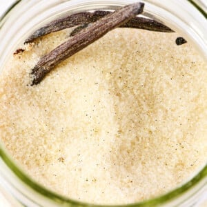 Vanilla beans and sugar in a glass container.