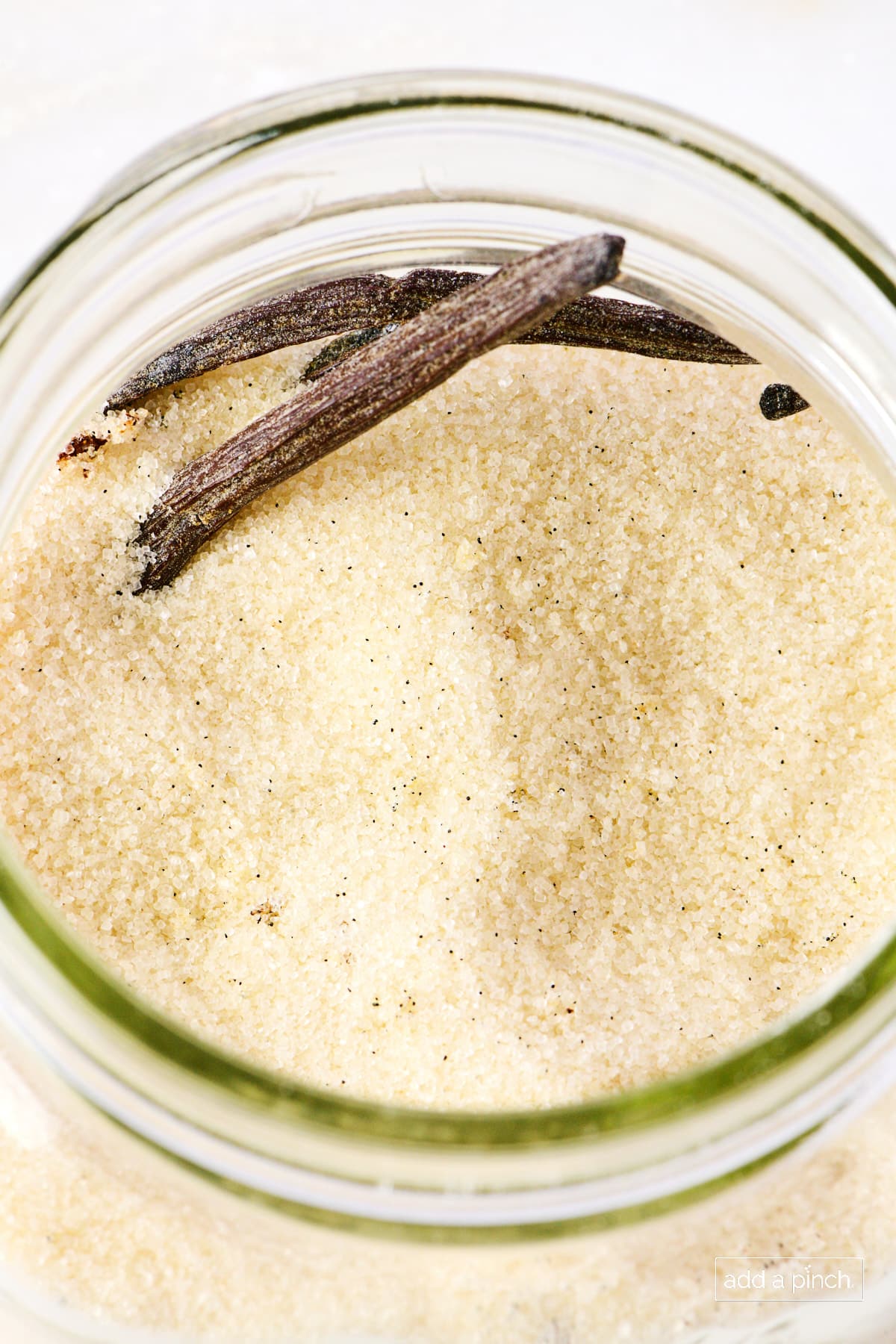 Vanilla beans and sugar in a glass container.
