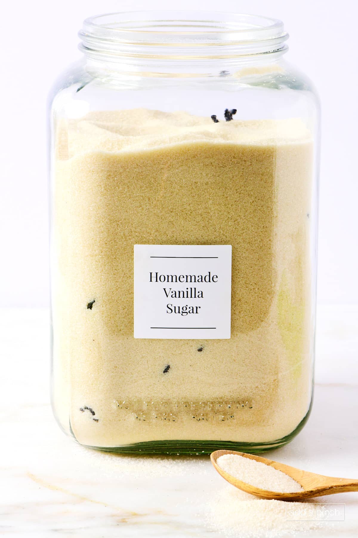 Vanilla sugar in a glass storage jar on a marble surface.