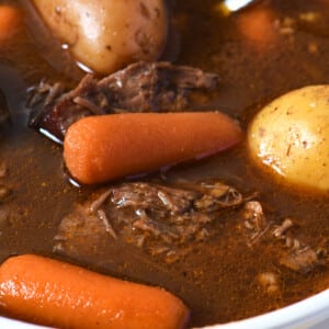 White soup bowl filled with venison stew with potatoes, onions, carrots.