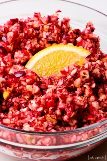 Cranberry relish in a glass bowl with an orange slice for garnish.