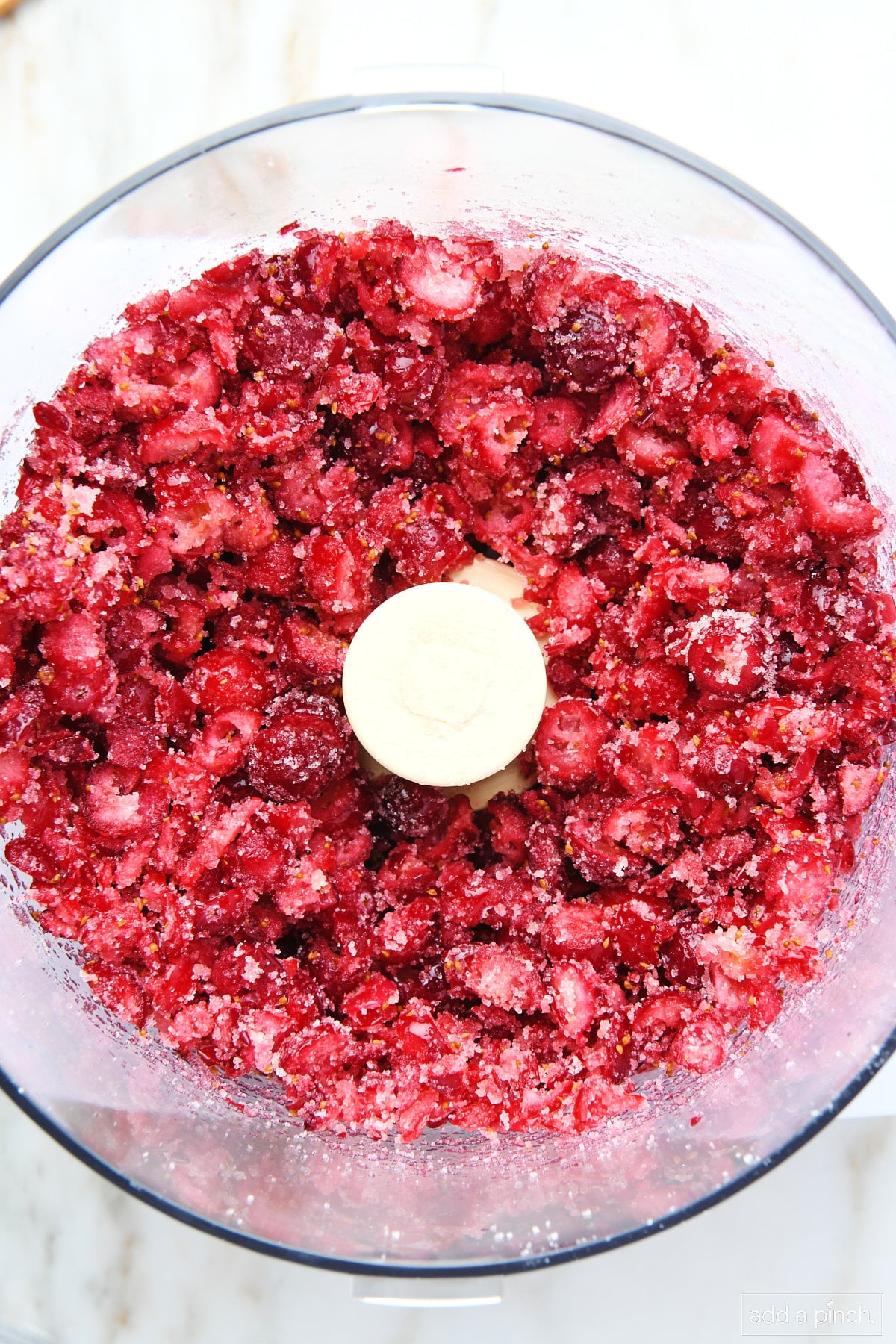 Fresh cranberries and sugar have been coarsely pulsed to combine in the food processor.