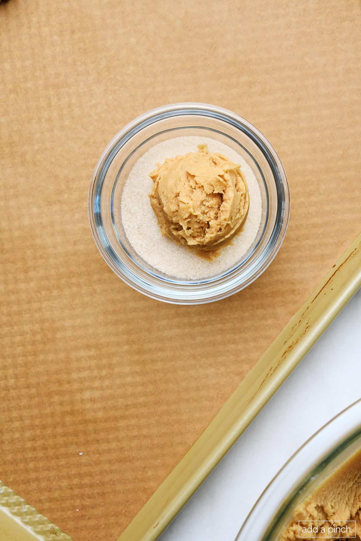 Scoop of peanut butter cookie dough in bowl of sugar.