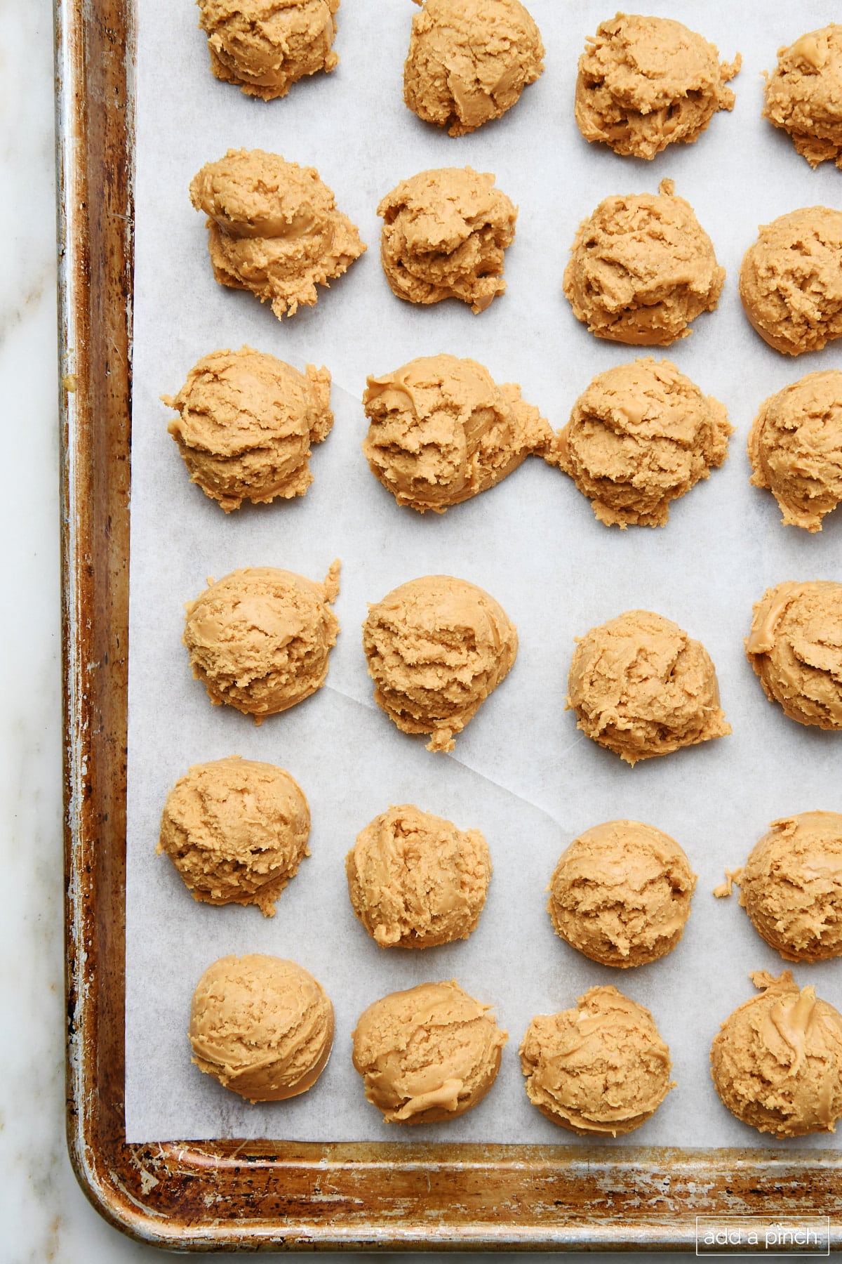 Peanut butter balls on a parchment lined baking sheet ready to be dipped in chocolate.