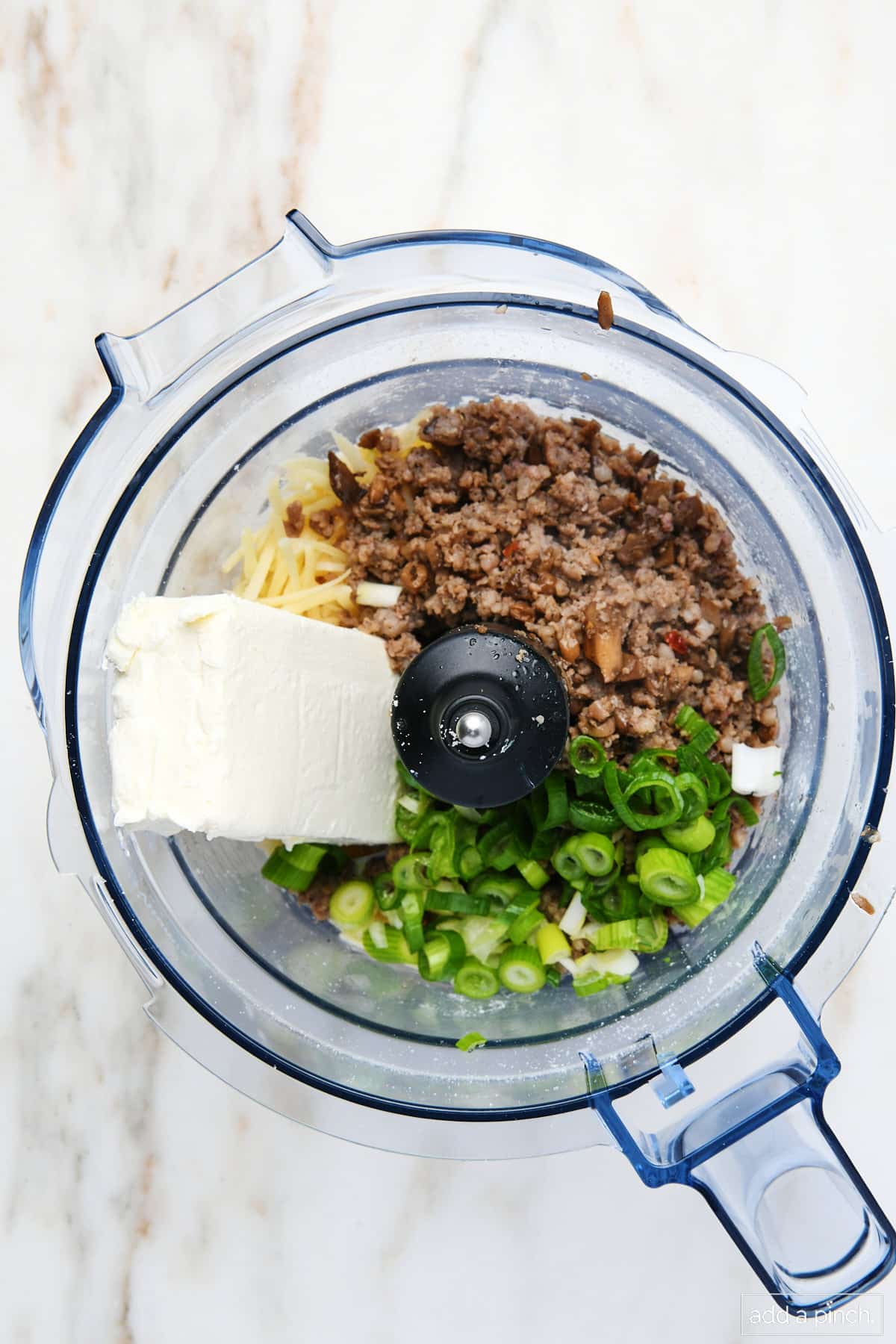 Stuffing ingredients for mushrooms like green peppers, cream cheese, parmesan cheese, and sausage all in a food processor. 