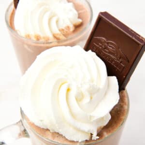 Mugs filled with hot chocolate and whipped cream, and a chocolate bar for garnish.