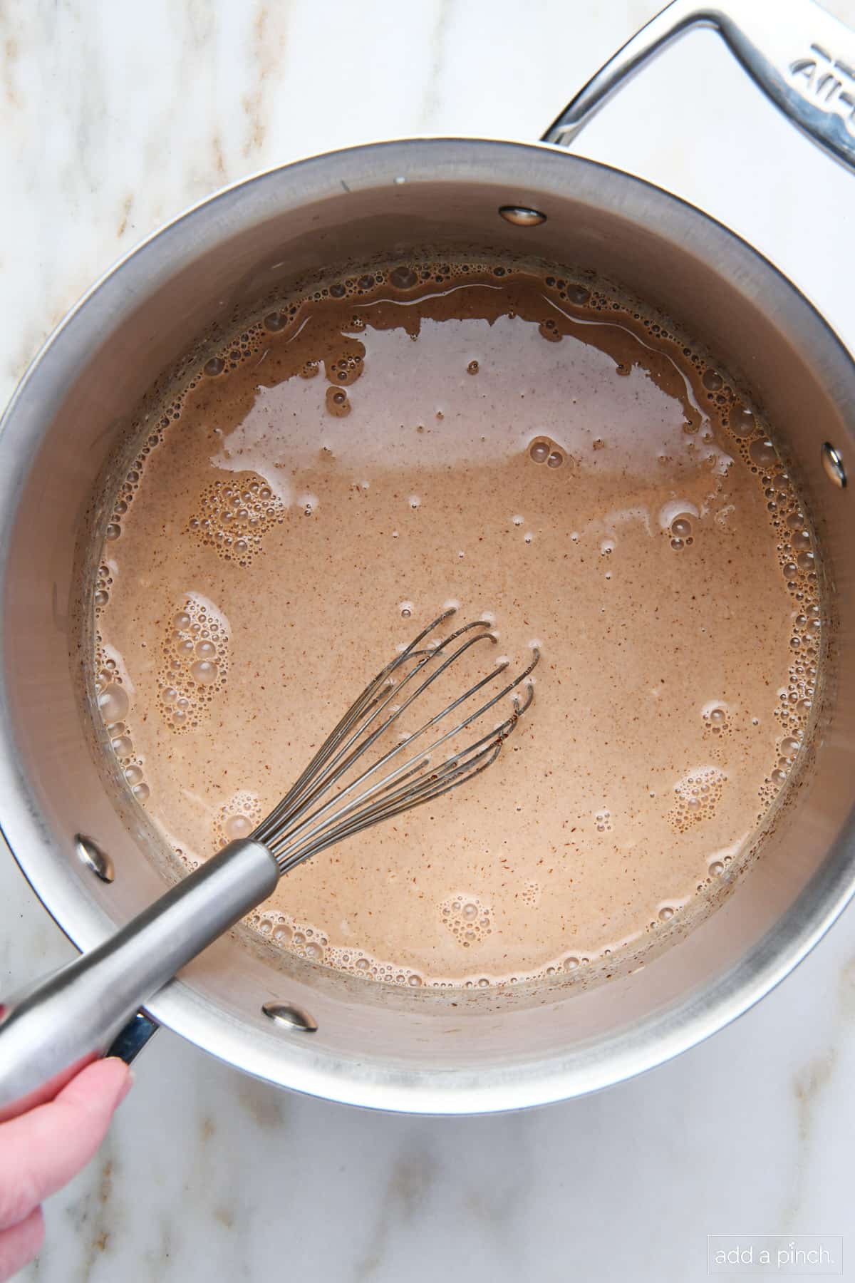Whisking chopped chocolate into warmed cream and milk.