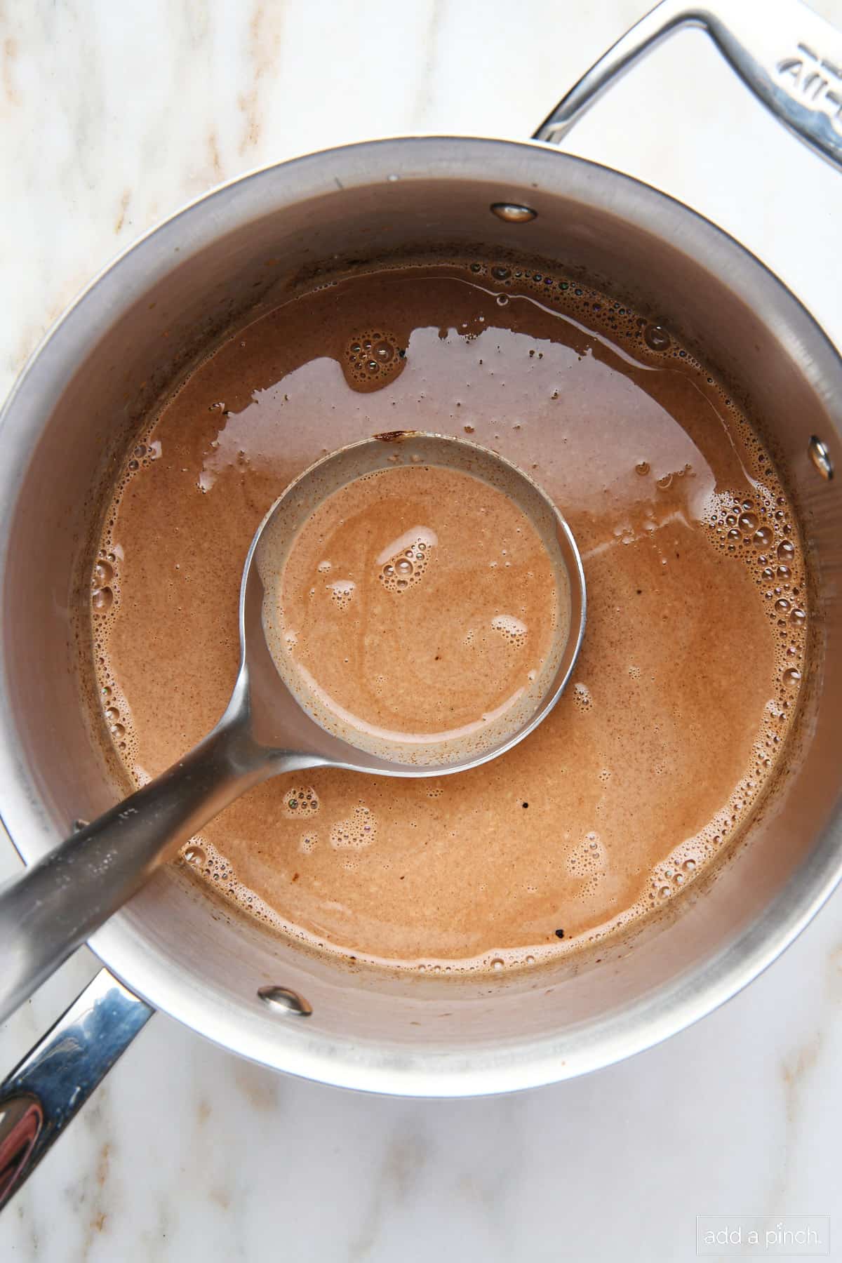 Hot chocolate in a heavy sauce pan with a ladle filled for serving.