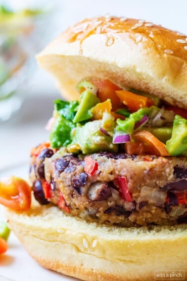 Black bean burger topped with avocado, onion, on a bun.