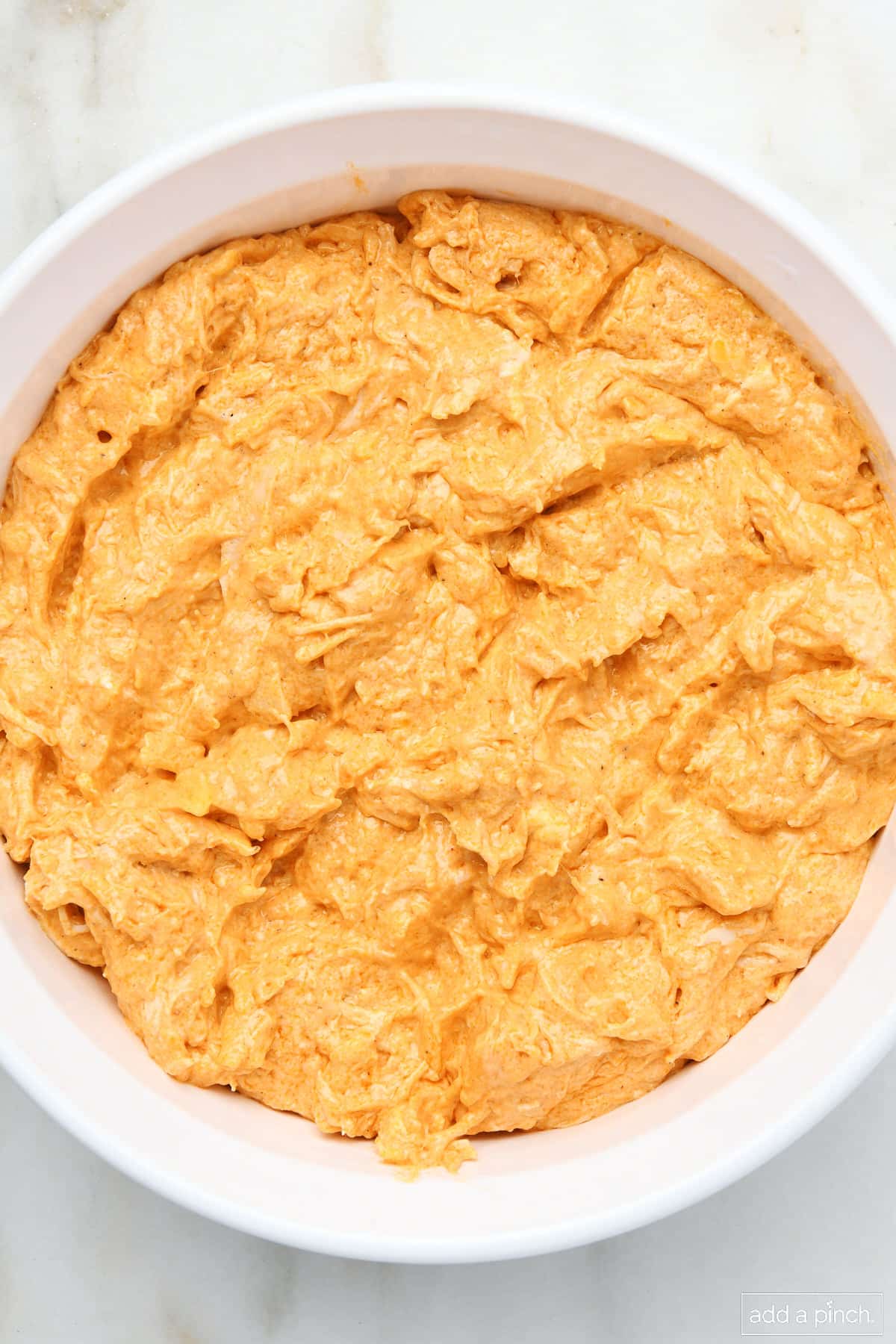 Buffalo Chicken Dip in a white baking dish on marble surface.