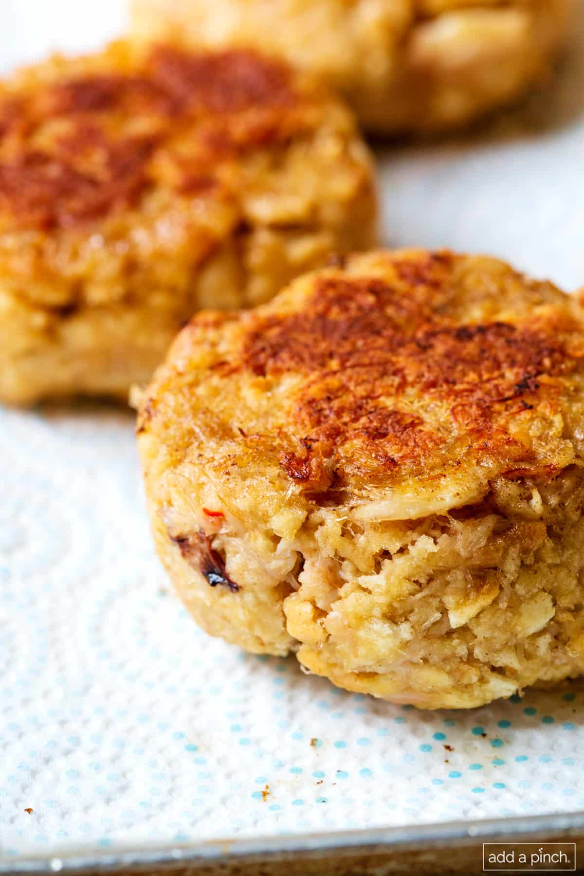 Paper towel holds some golden brown crab cakes to drain.