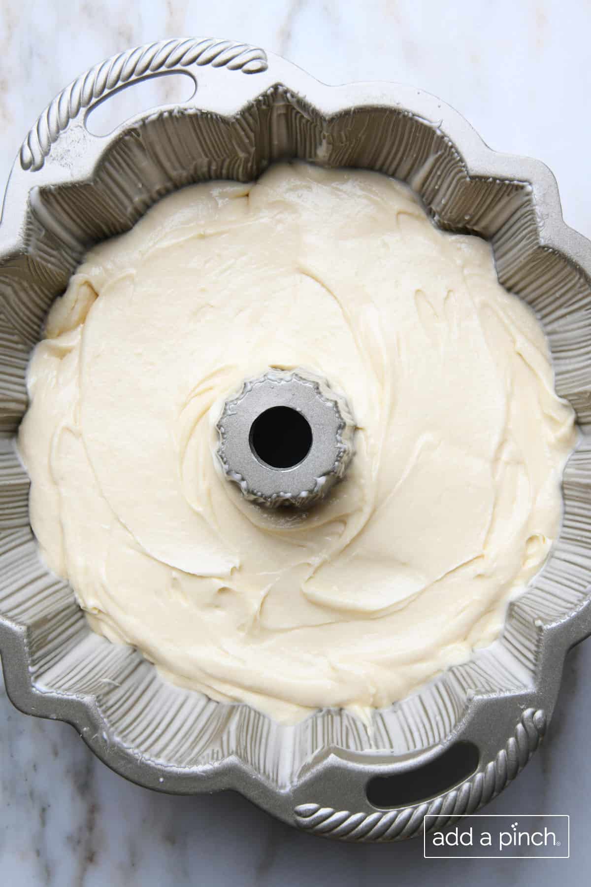 Bundt pan with handles holds cake batter. 