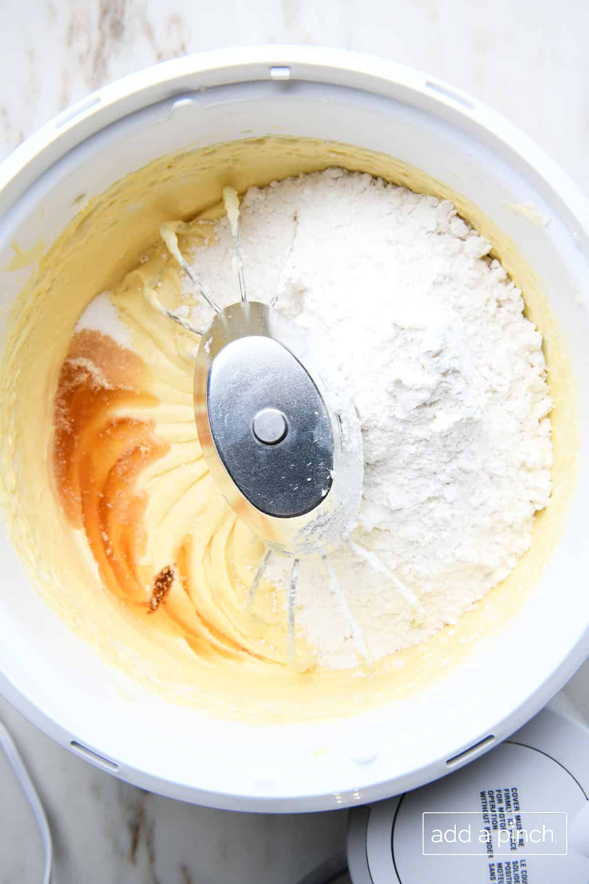 Stand mixer bowl has creamed ingredients with flour and vanilla added ready to mix. 