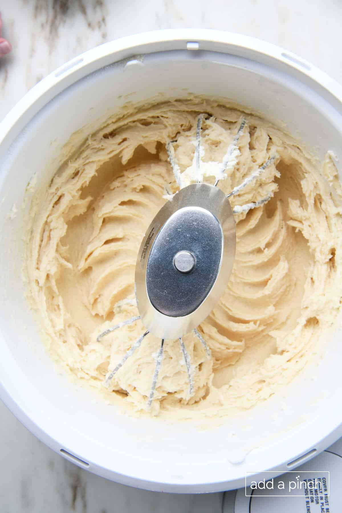 Bowl of stand mixer holds butter, cream cheese and sugar after creamed together.