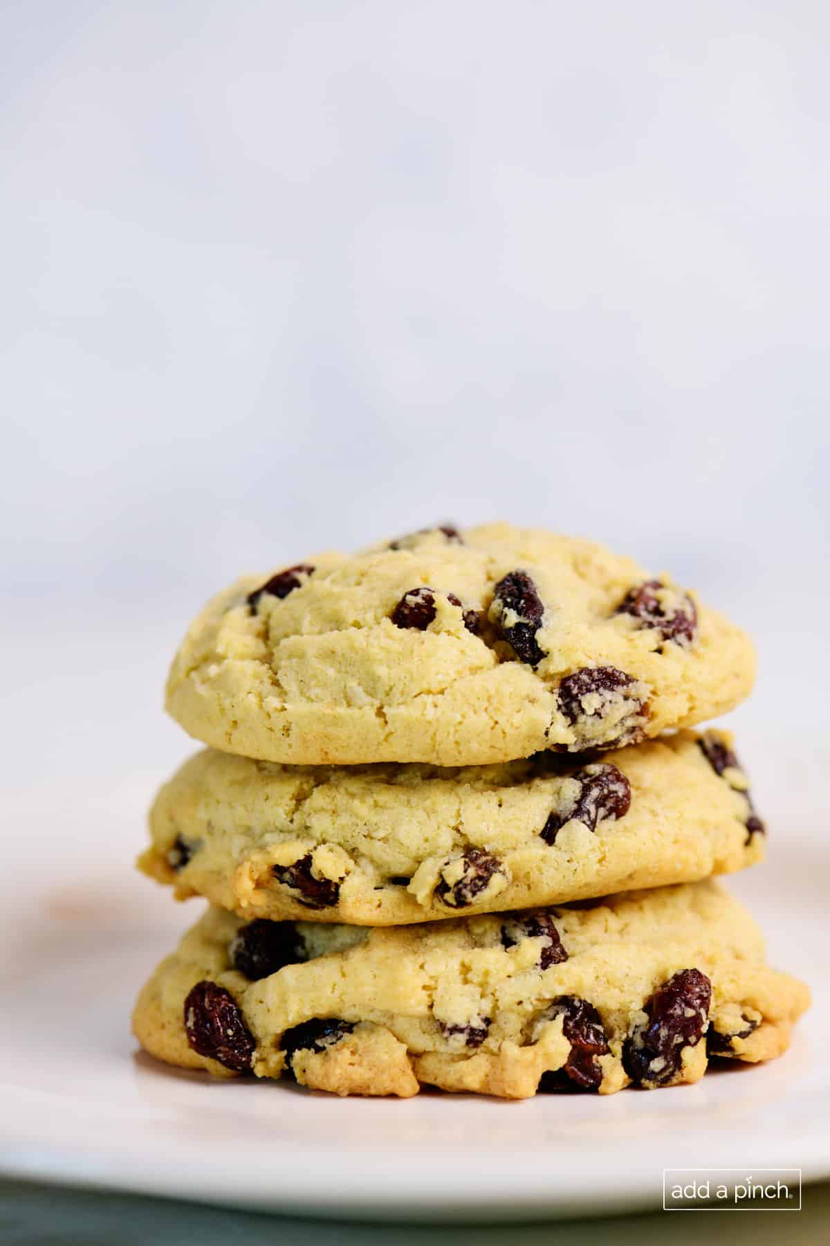 Stack of baked oatmeal raisin cookies on a white plate.