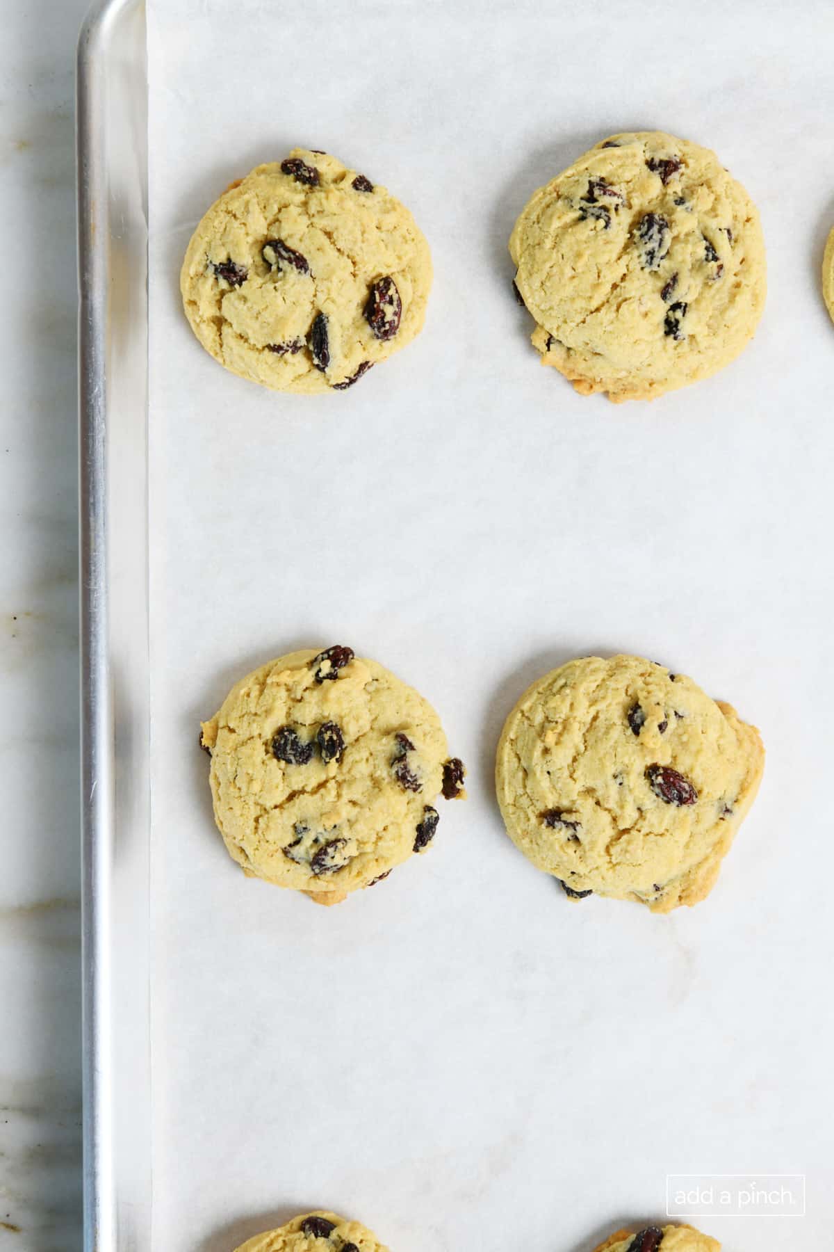 Freshly baked oatmeal raisin cookies on a baking sheet.