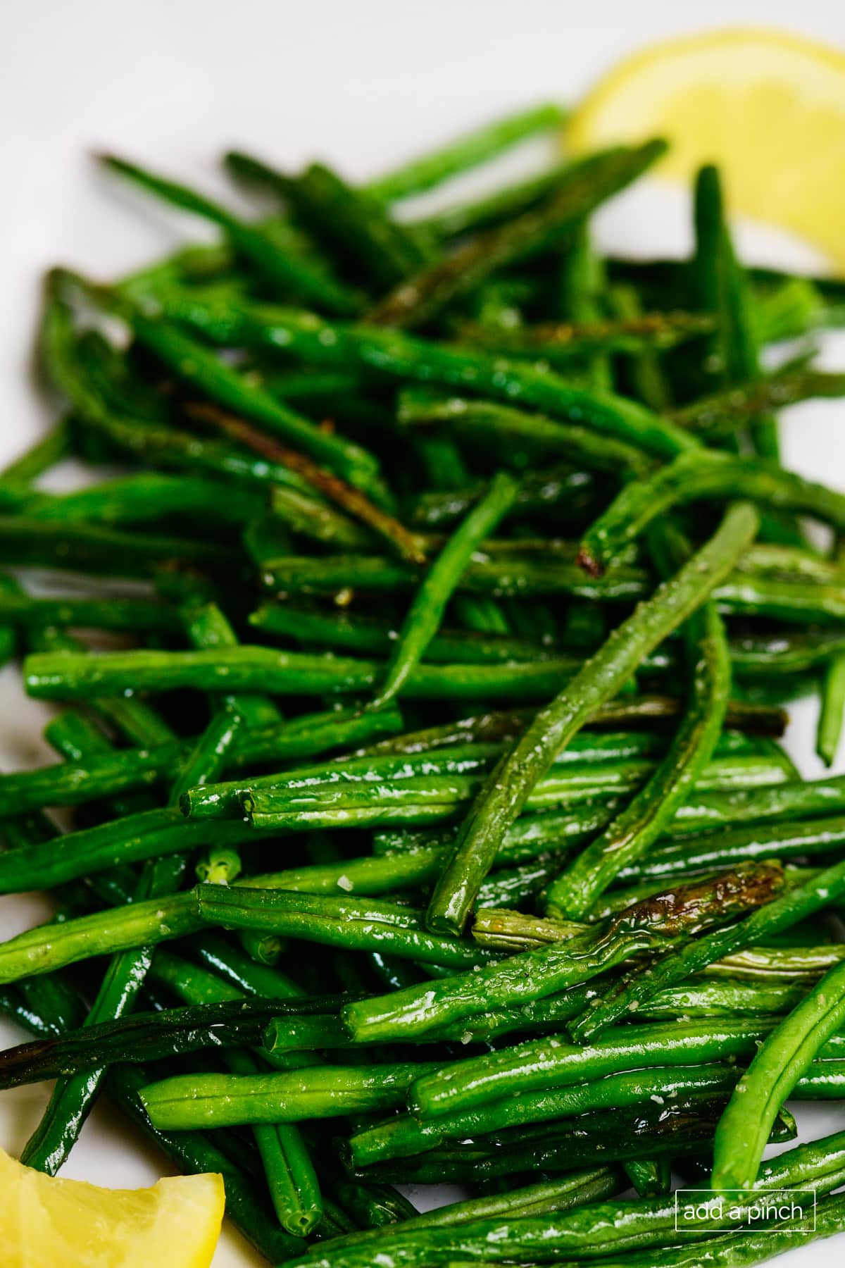 Roasted green beans with lemon wedges.