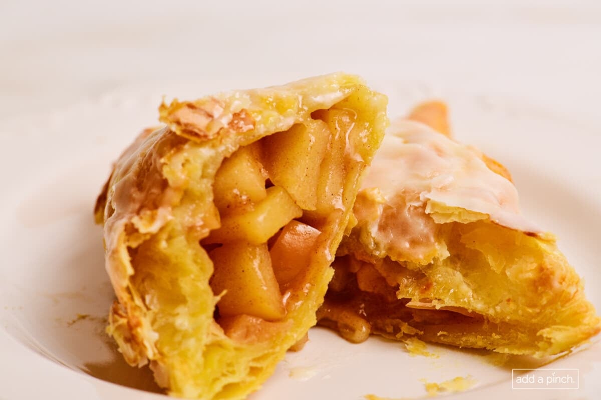 Apple turnovers cut in half on a white plate.