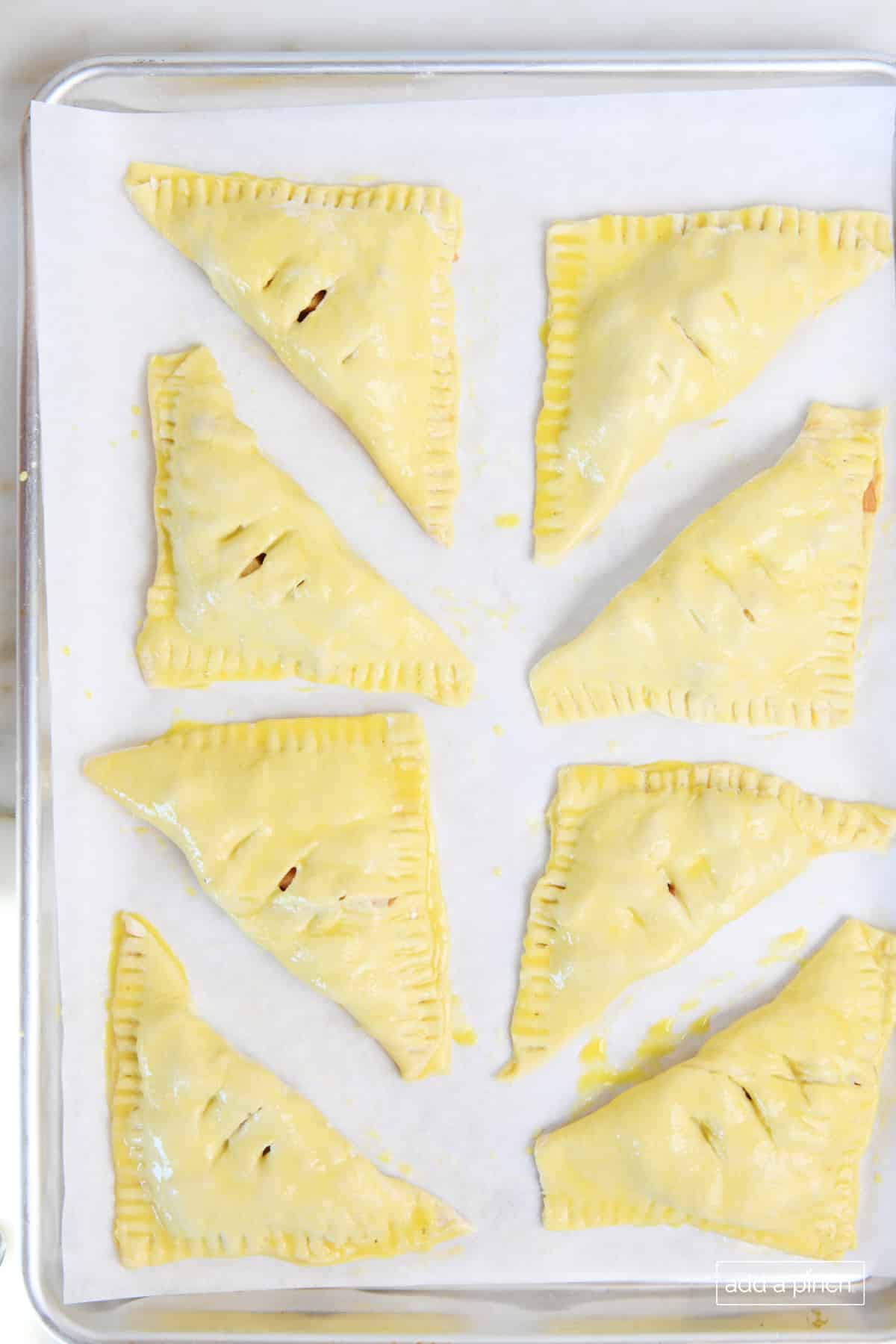 Brush the turnovers with egg wash and cut slits in the top.