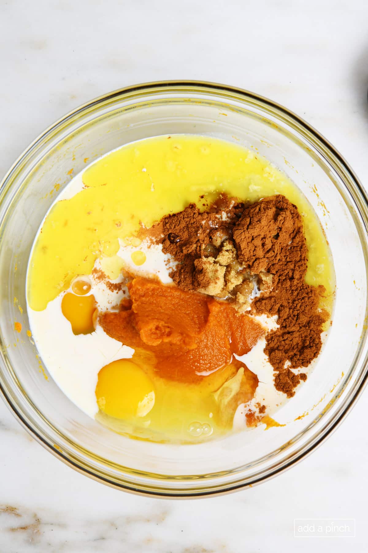 Ingredients for mini pumpkin pie filling in a glass bowl.