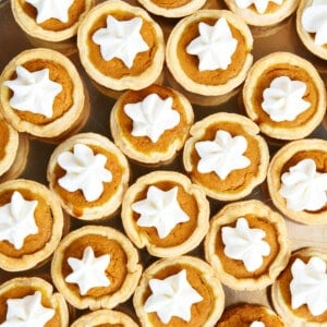 Mini pumpkin pie topped with whipped cream on a pewter plate.