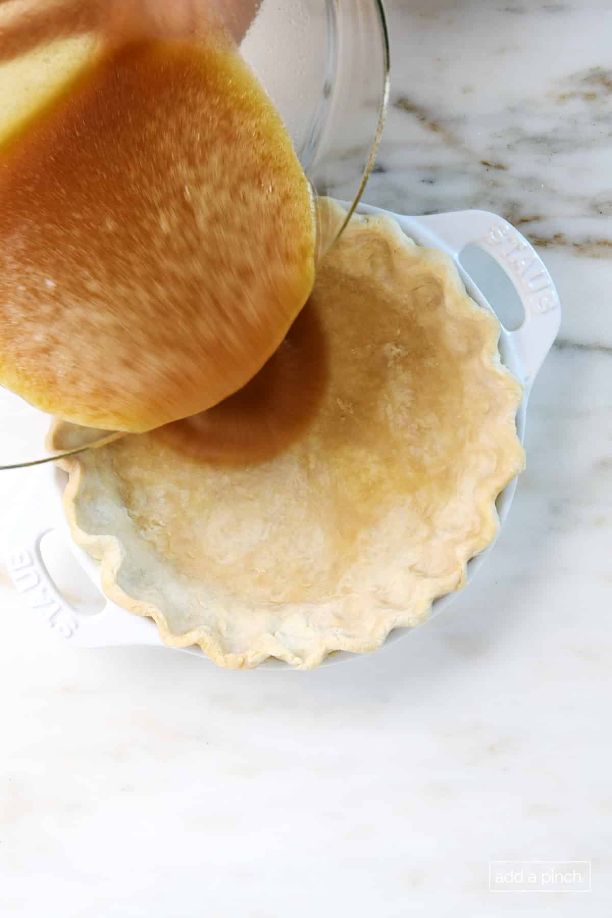 Pouring mixed pie filling into an unbaked pie crust.