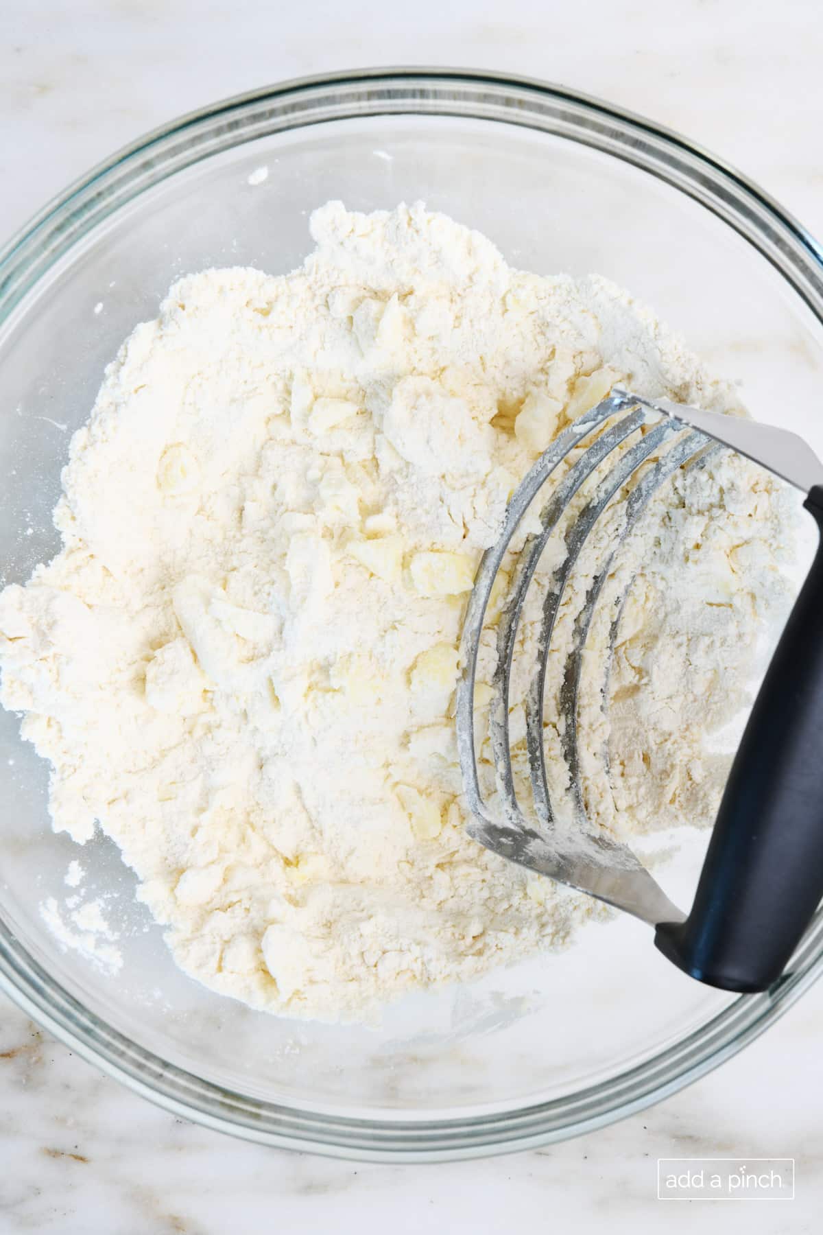 Pastry blender is used to blend the pie crust ingredients into a crumb texture.