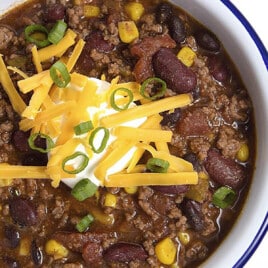 Best taco soup in a white bowl topped with sour cream, cheese, and green onions.