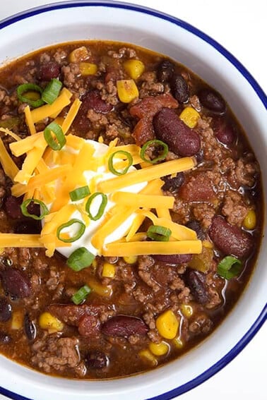 Best taco soup in a white bowl topped with sour cream, cheese, and green onions.