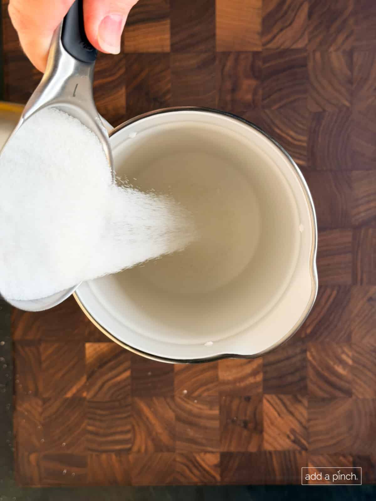 Pouring sugar into pitcher for fresh lemonade.