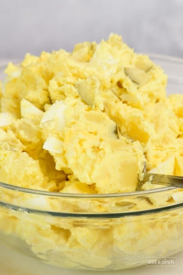 Closeup of a bowl of Southern potato salad in a glass bowl.