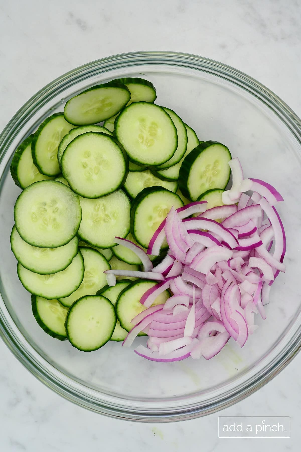 Cucumber and red onion in a bowl.