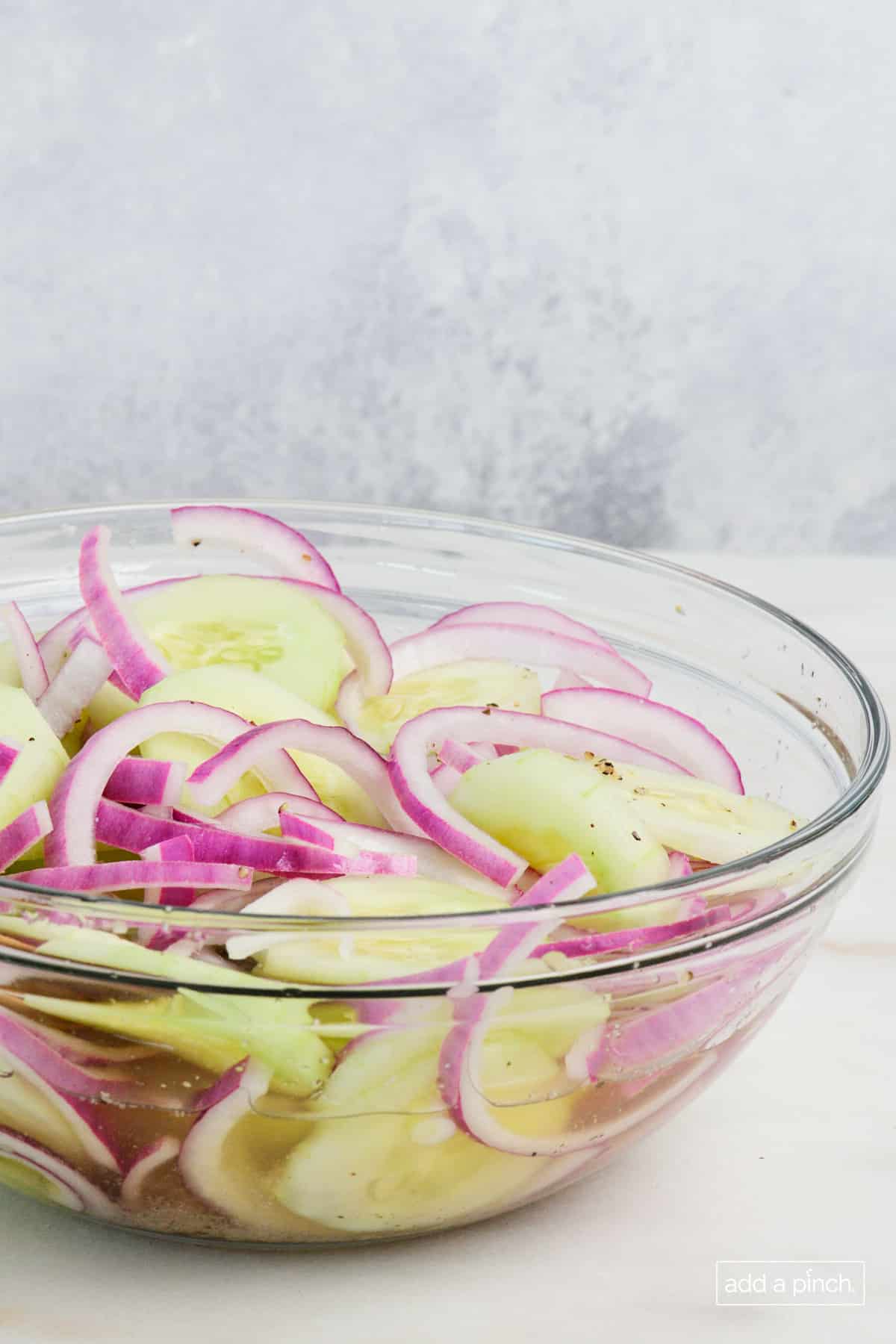 Side view of glass bowl of cucumber onion salad.