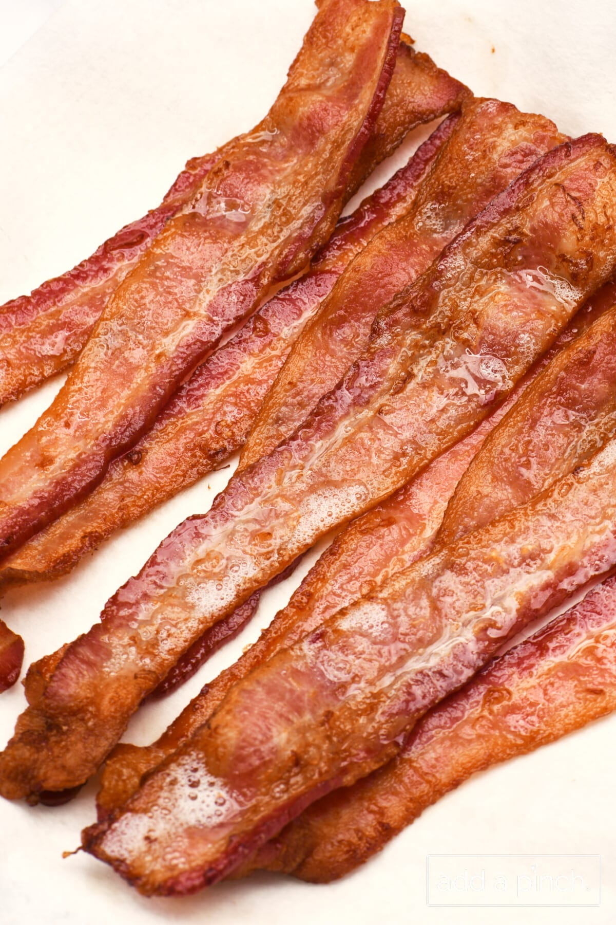 Stack of crispy air fryer bacon on a towel lined plate.