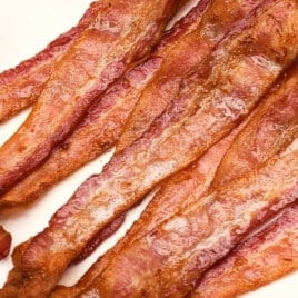 Stack of crispy air fryer bacon on a towel lined plate.