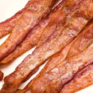 Stack of crispy air fryer bacon on a towel lined plate.